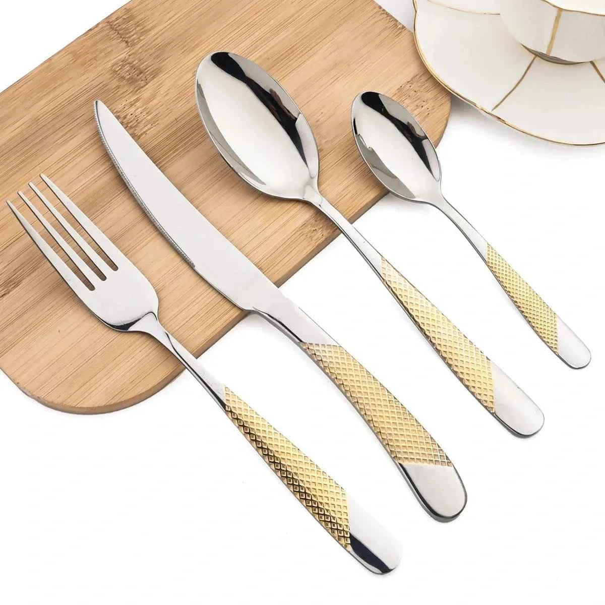 Détail des couverts 24 pièces Gold Silver : couteau, fourchette et cuillères avec têtes dorées et manches argentés à texture diamantée sur une planche en bois