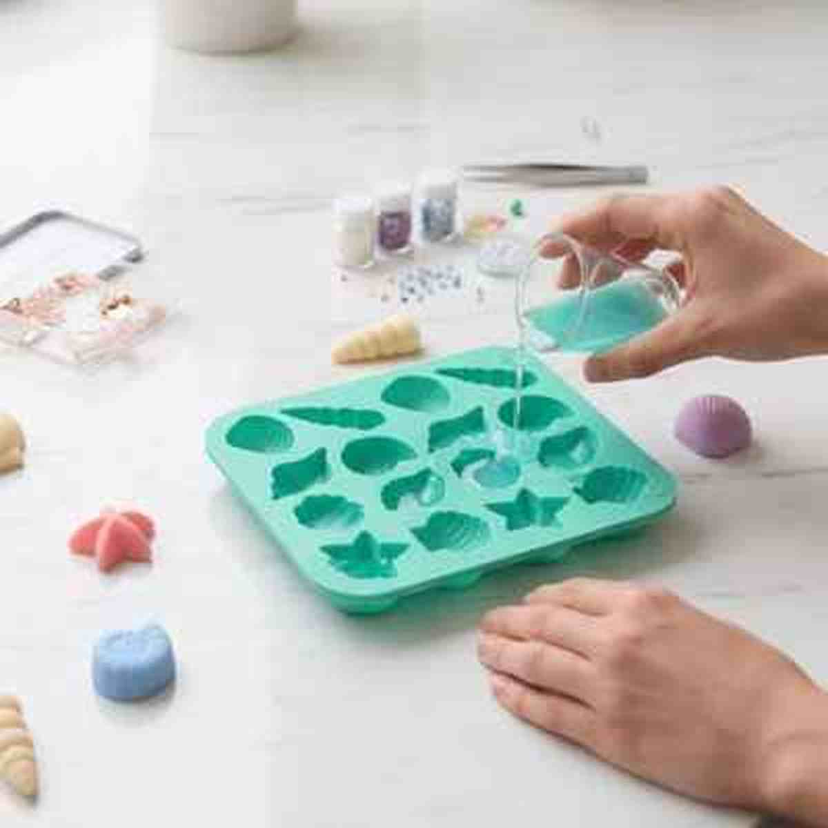 Moule en silicone vert utilisé pour la création artisanale (savon ou résine) avec des empreintes en forme de coquillages et étoiles de mer.