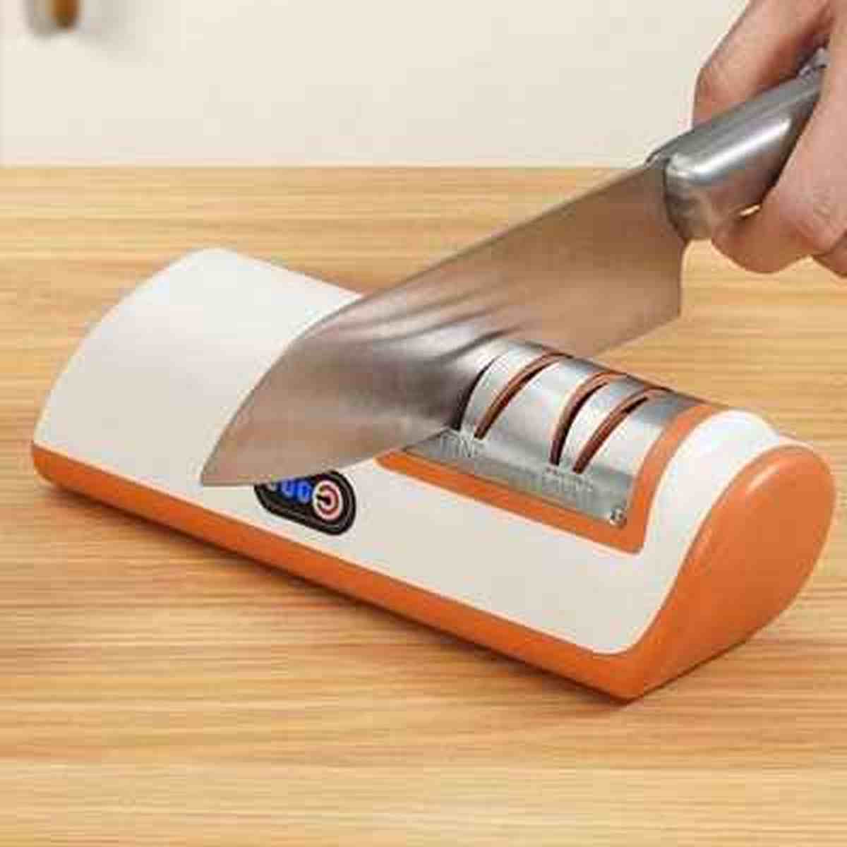 Utilisation de l'aiguiseur électrique UltraSharp pour affûter un couteau de chef avec une grande stabilité sur un plan de travail en bois.