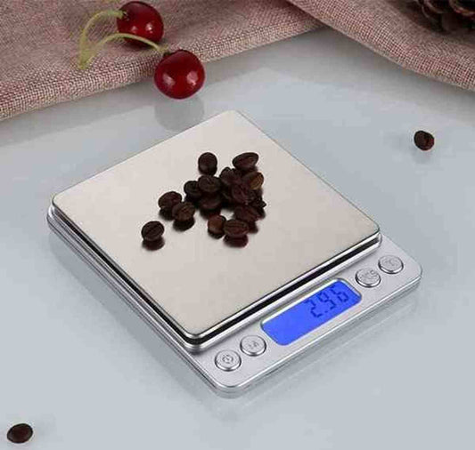 Balance de cuisine électronique en acier inoxydable affichant 2.96g, avec des grains de café sur le plateau et des cerises en décor