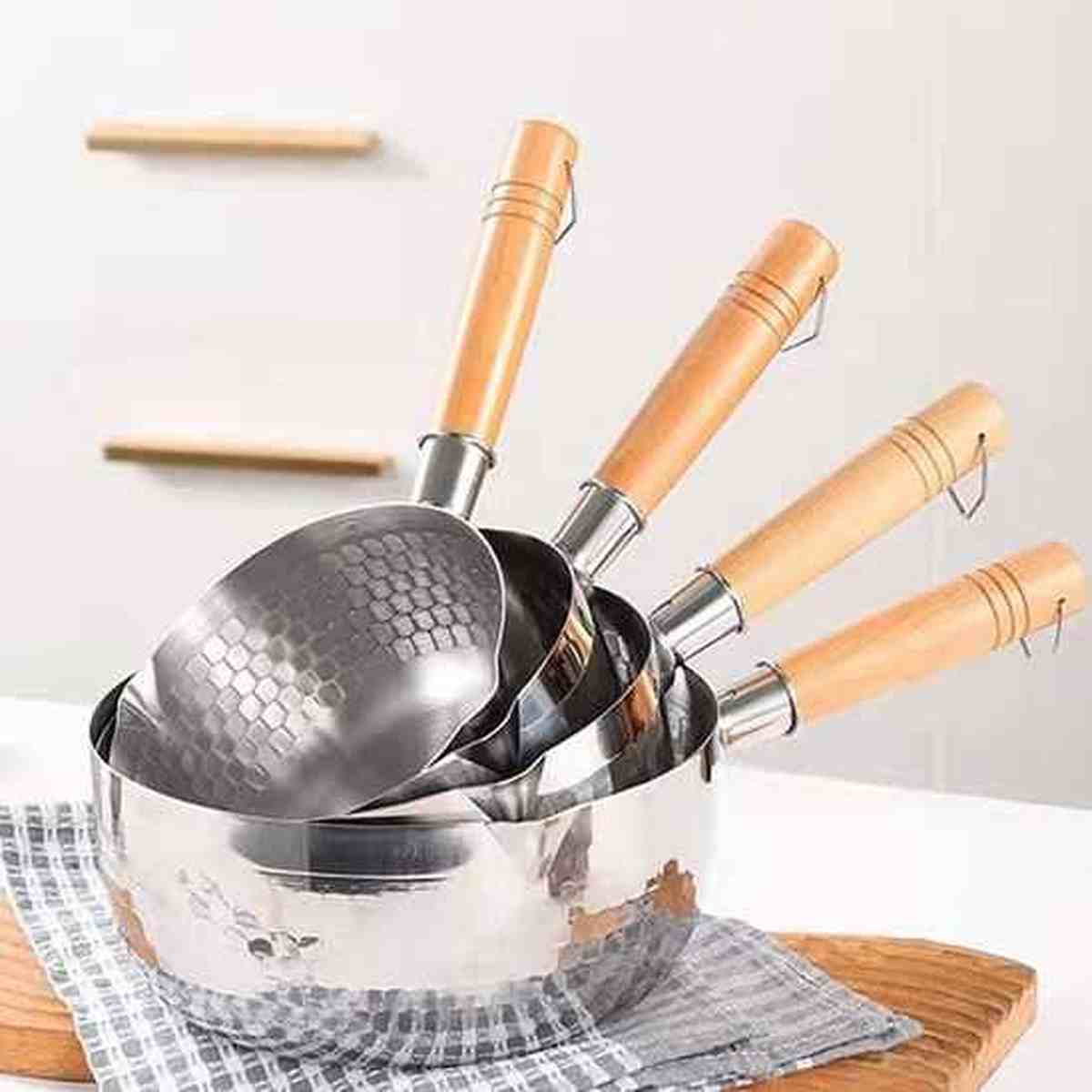 Série de casseroles en acier inoxydable avec manches en bois ergonomiques et finition intérieure martelée.