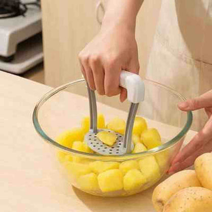 Utilisation du presse-purée ergonomique pour écraser facilement des morceaux de pommes de terre cuites dans un saladier en verre.