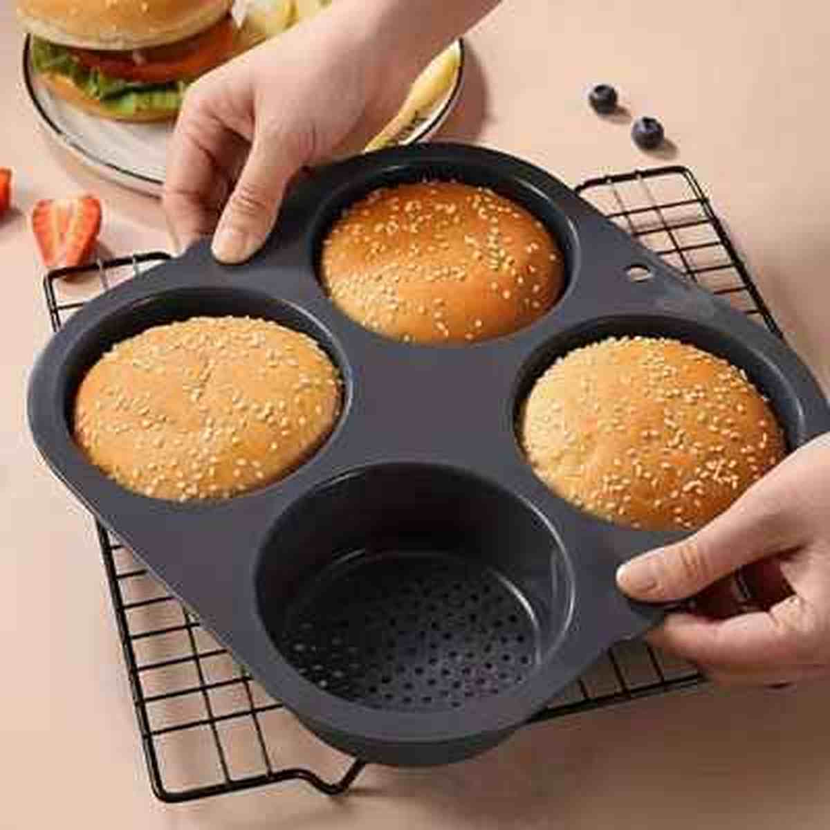 Moule à pains burger en silicone noir avec fond perforé pour une circulation d'air optimale et une croûte croustillante.