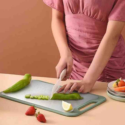 Préparation de fruits et piments sur une planche à découper grise, illustrant sa polyvalence pour tous types d'aliments.