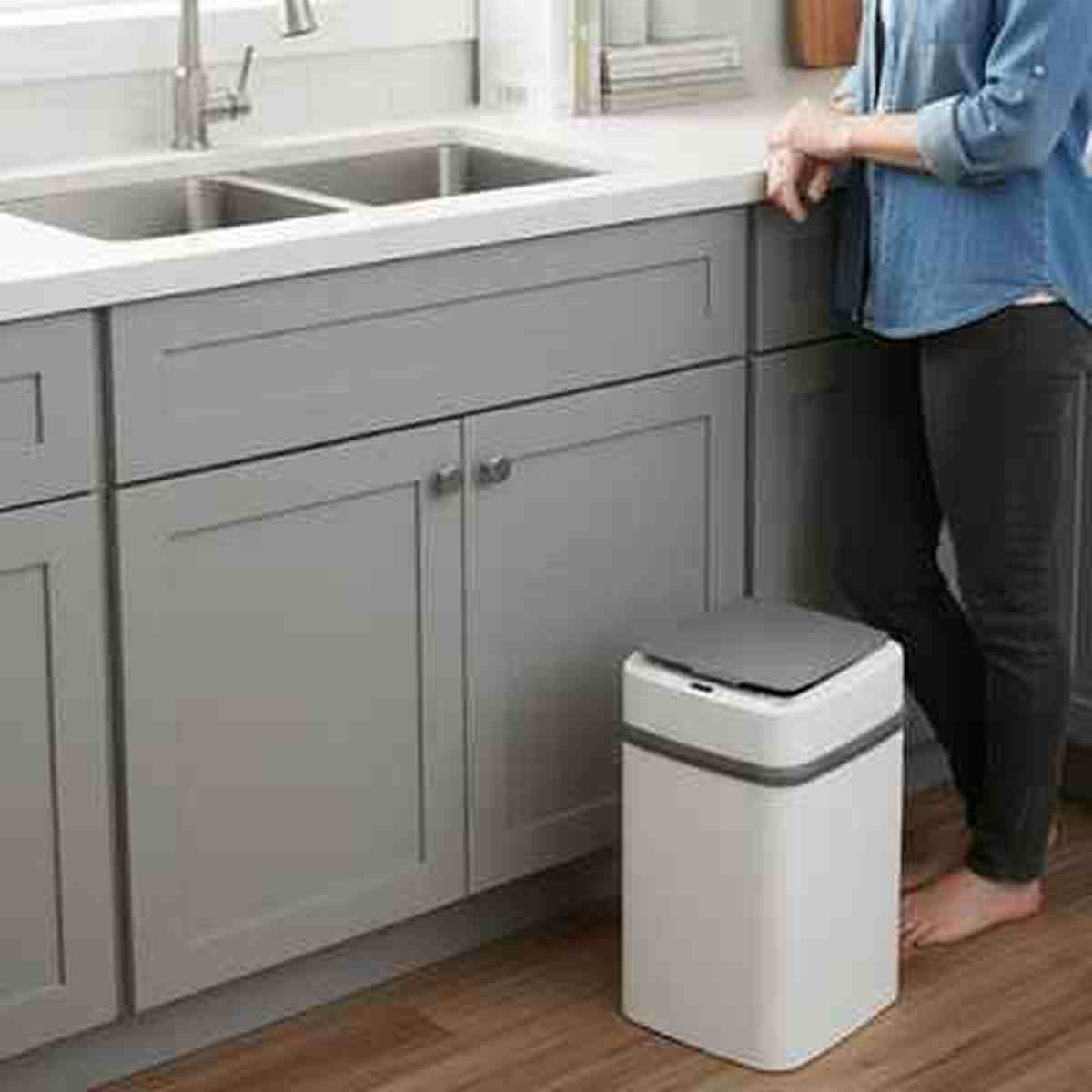 Poubelle automatique Design Fresh blanche avec couvercle gris fermée, placée à côté d'un meuble de cuisine gris élégant.