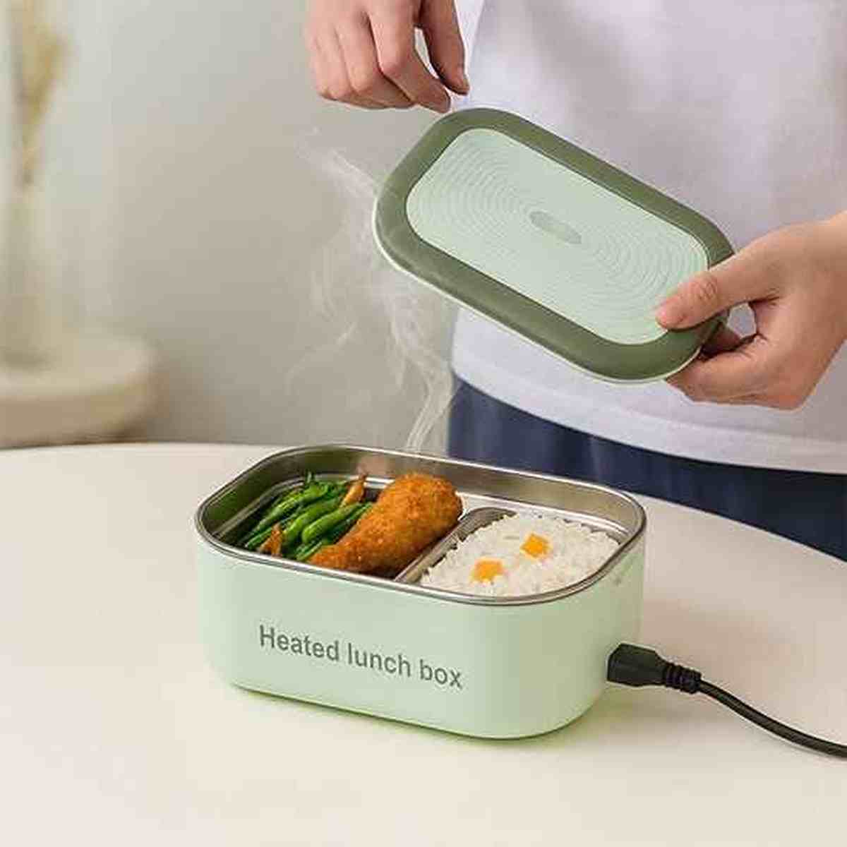 Lunch box électrique BureauGourmet branchée dégageant de la vapeur, montrant un repas chaud composé de riz, poulet et haricots verts