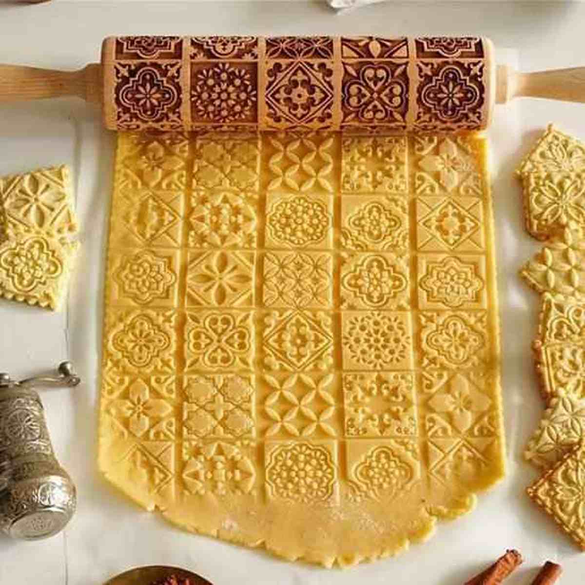 Grande pâte à biscuits étalée affichant des motifs géométriques et floraux complexes et réguliers créés avec le rouleau gravé Artisan Pro.